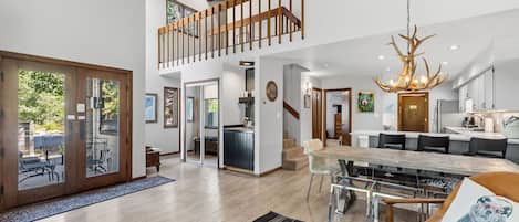 A spacious living area with a dining table, a kitchen, and a staircase leading to an upper level.