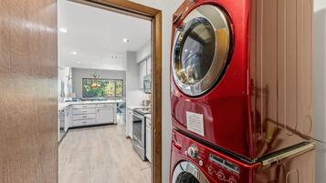 A modern kitchen with white cabinets, a built-in oven, and a window overlooking the room.