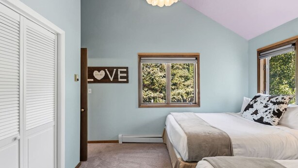 Quarto com cama, janela com vista, placa na parede e porta.