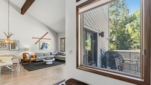 Uma sala de estar moderna com área de jantar, uma janela grande e vista para o exterior.