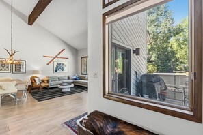 Ein modernes Wohnzimmer mit Essbereich, einem großen Fenster und Blick ins Freie.