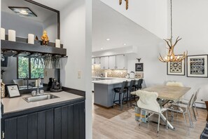 Eine moderne Küche mit einer großen Kochinsel, einem Essbereich mit Holztisch und -stühlen sowie einer Kronleuchter mit Geweihen.