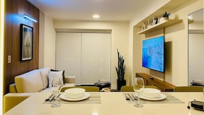 Ein moderner Essbereich mit Tisch für zwei Personen, einem an der Wand montierten Fernseher und einem Schiebetürenschrank.