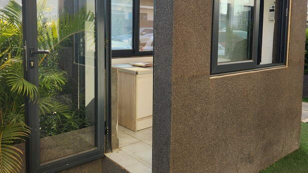 Un edificio moderno con puerta de cristal, un pequeño escritorio y vista a la calle.