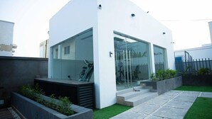 Una casa moderna con fachada blanca, amplios ventanales y un pequeño jardín delantero con un camino.