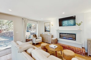 A living room with a fireplace, a sofa, a coffee table, and a television mounted above the fireplace. - Lakeview Cabin at the Cove (Zephyr Cove)