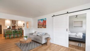 A modern living room with a sofa, coffee table, and dining area with chairs. - The Modern Cottage Bend (Bend)