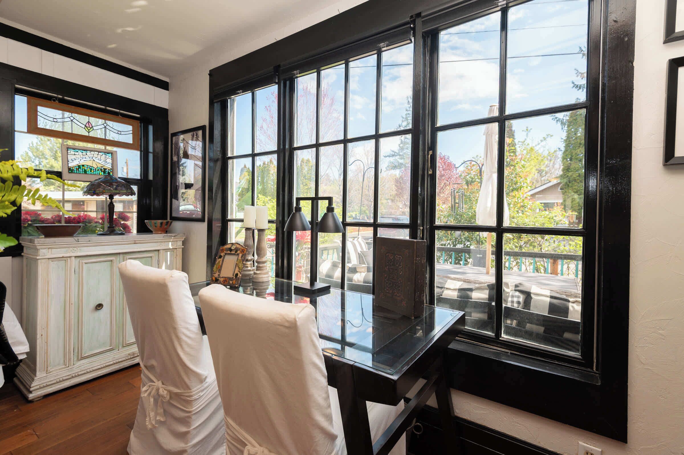 A room with a large window, a white cabinet, and two chairs.