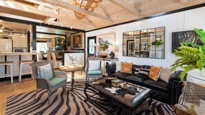 A spacious living area with a high ceiling, a zebra-patterned rug, a black leather sofa, and a glass coffee table. - Private Pickleball Court + Riverfront Bend Retreat (Bend)