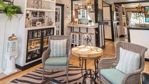 A spacious room with a high ceiling, wooden beams, wicker furniture, and a kitchen area. - Private Pickleball Court + Riverfront Bend Retreat (Bend)