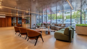 Eine großzügige Lobby mit moderner Einrichtung, großen Fenstern und Blick auf parkende Autos.