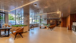 Eine großzügige Lobby mit modernem Design, inklusive einer Sitzecke mit Sofas und Sesseln, einem Couchtisch und einer Rezeption.