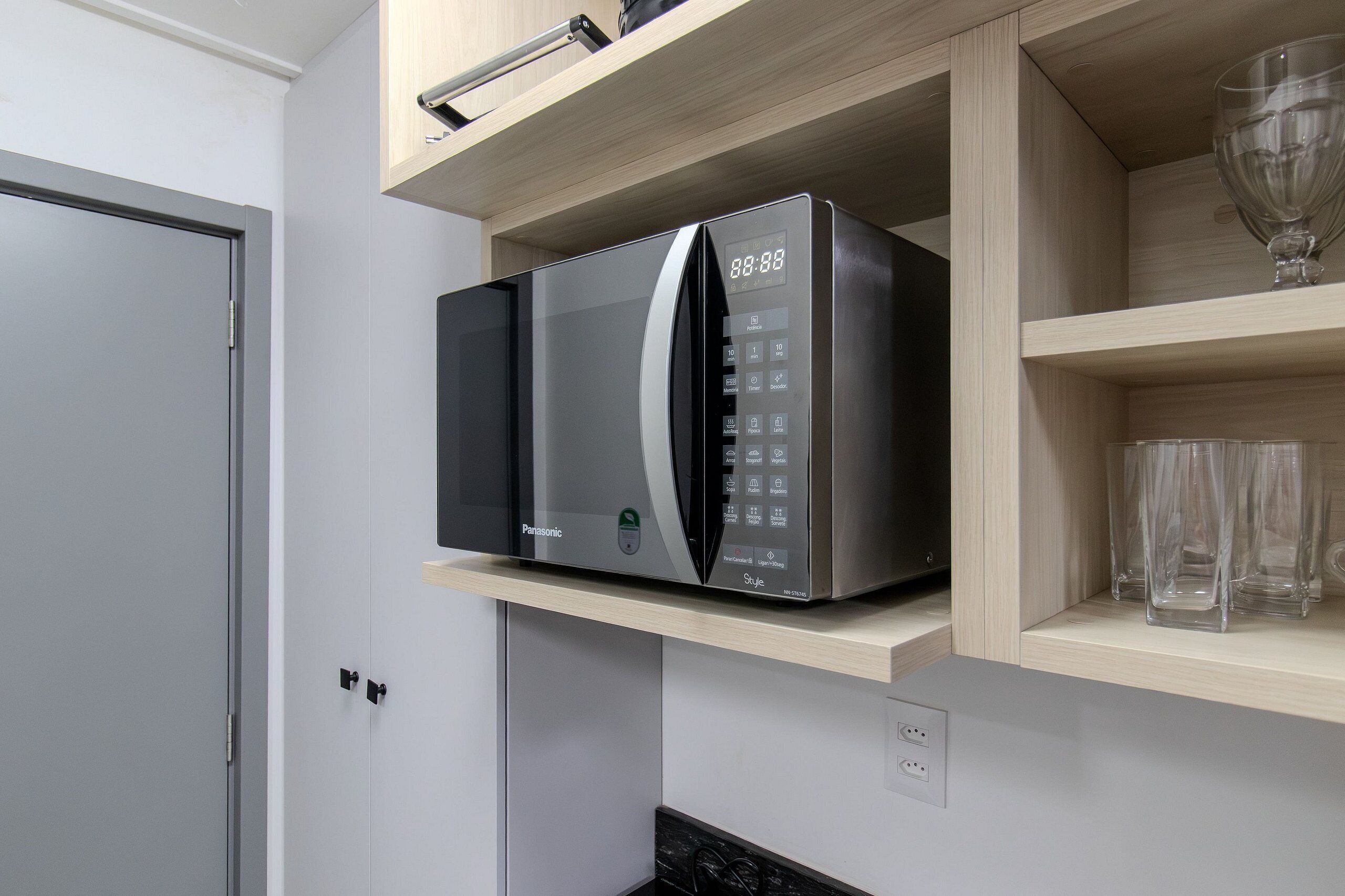 Una cocina con microondas en un estante, una puerta y una encimera.