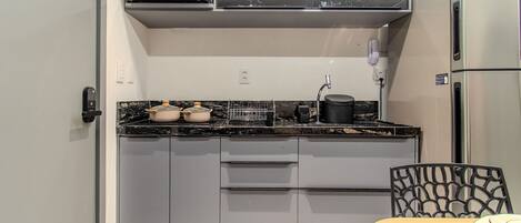 A compact kitchen with a microwave, stove, and refrigerator. There is a dining table with chairs.