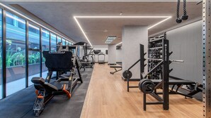 Ein modernes Fitnessstudio mit Trainingsgeräten, großen Fenstern und Holzboden.