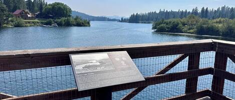 A wooden deck overlooking a lake with a signboard.