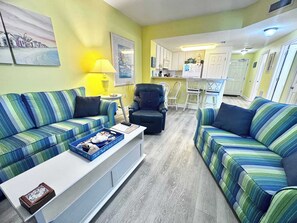 Ein Wohnzimmer mit gestreiften Sofas, einem Couchtisch, einer Lampe und einem Bild an der Wand.