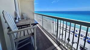 Een balkon met uitzicht op het strand, een tafel en stoelen.