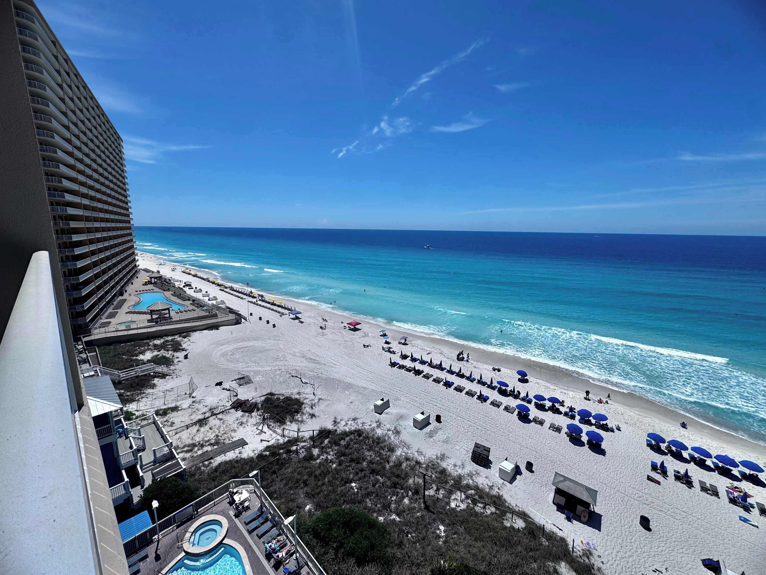 A hotel with a pool, beach, and ocean view.