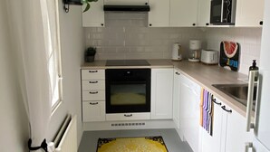 Eine Küche mit weißen Schränken, einer Mikrowelle, einer Kaffeemaschine und einem gemusterten Teppich.