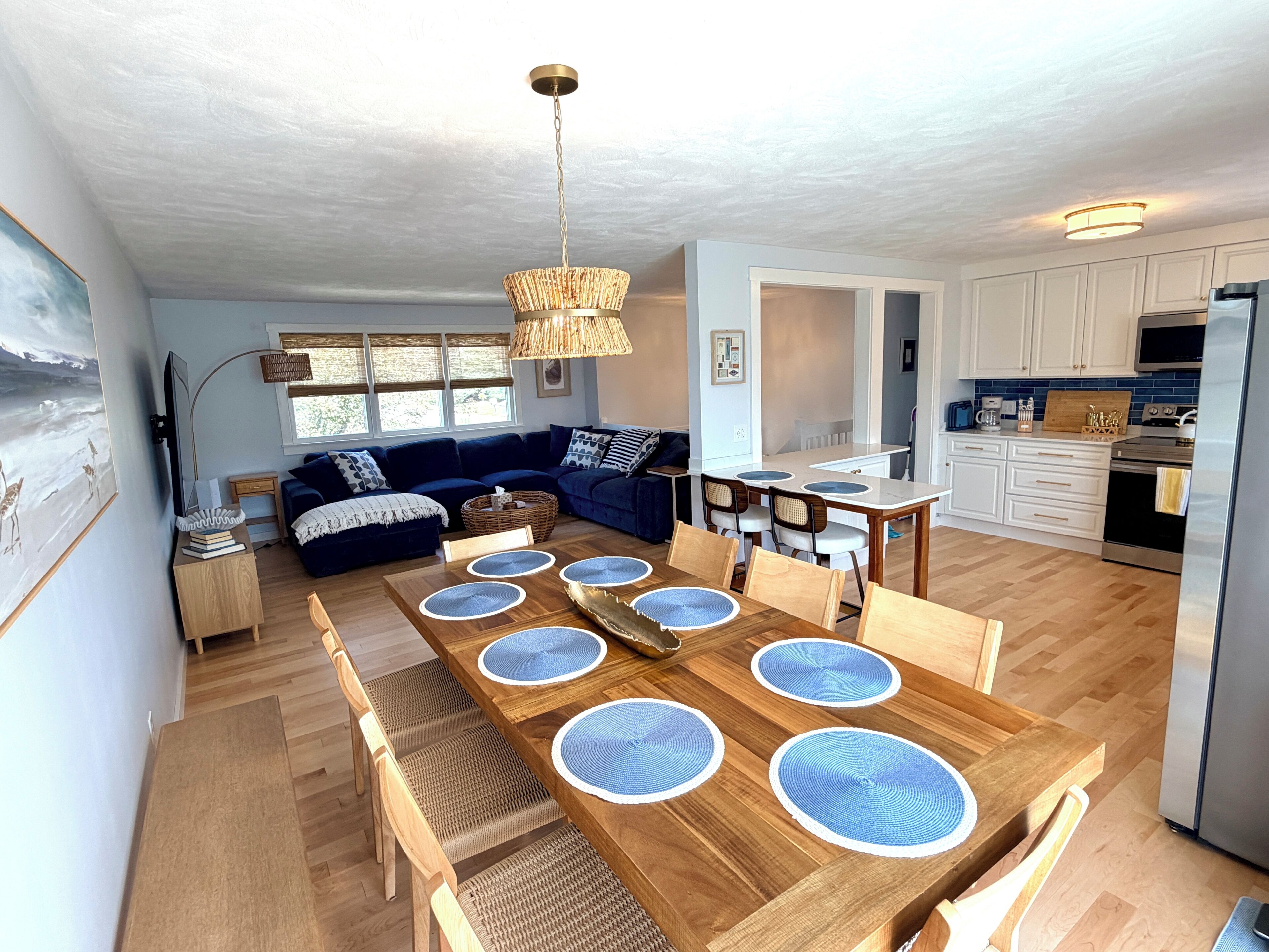 Ein modernes Wohnzimmer mit Essbereich, Holzboden und einer Küche im Hintergrund.