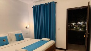 A bedroom with a bed, blue curtains, a night view through an open door, and a night light.