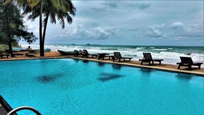 A swimming pool with lounge chairs and a view of the ocean.