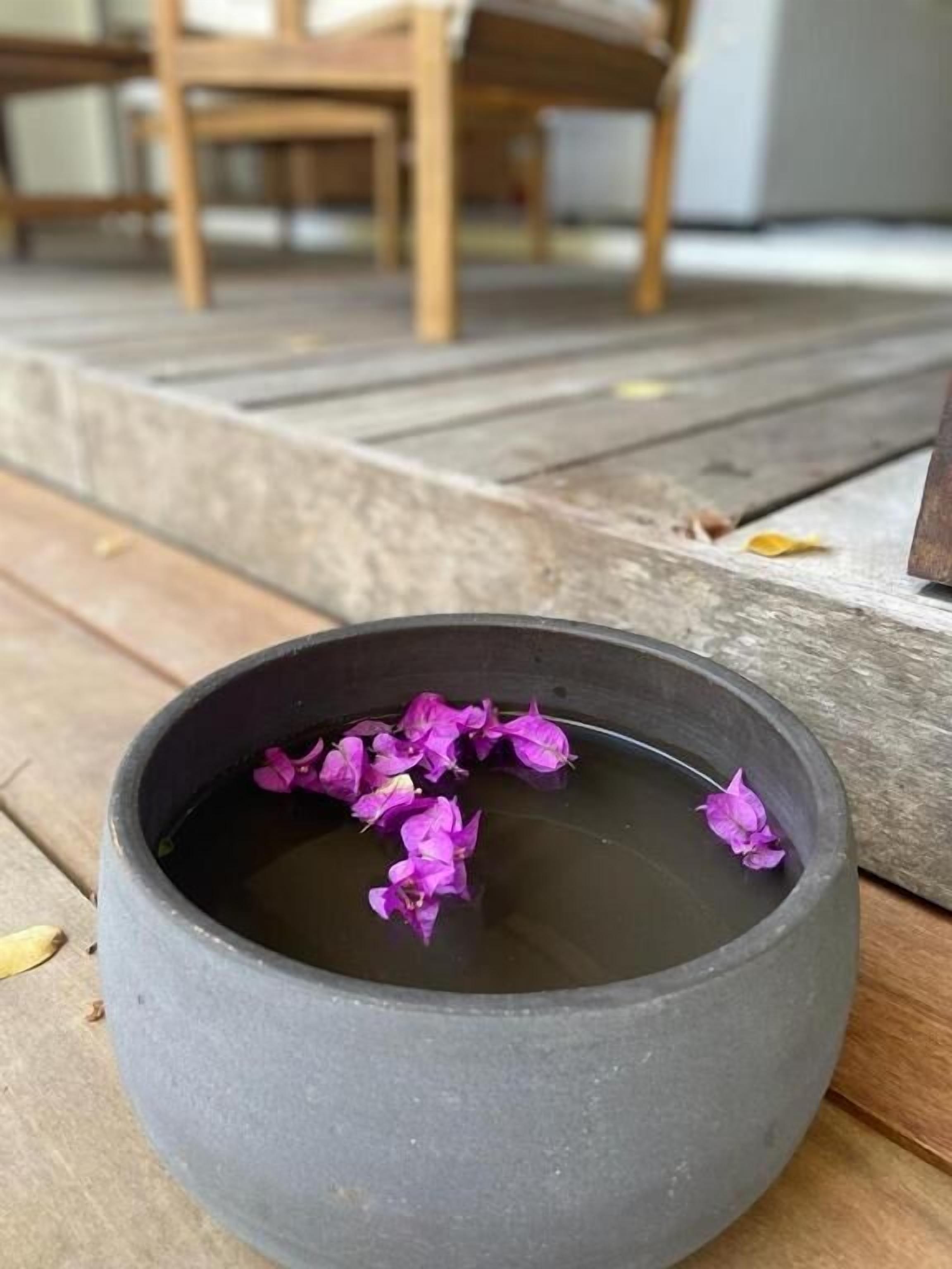 A black bowl with purple flowers on a wooden surface.