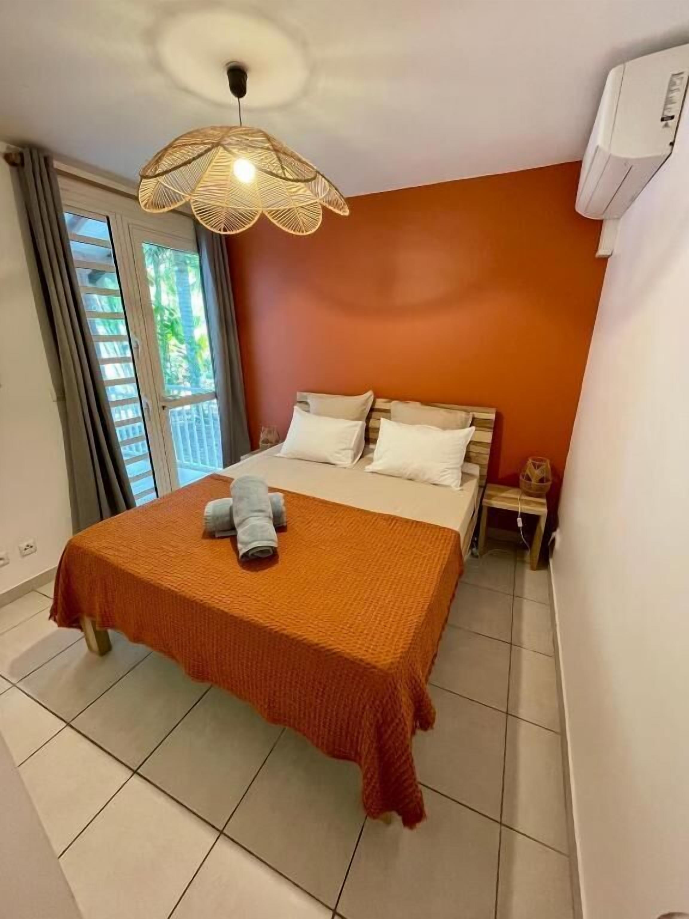 A bedroom with a bed, a nightstand, a lamp, and a window with curtains.