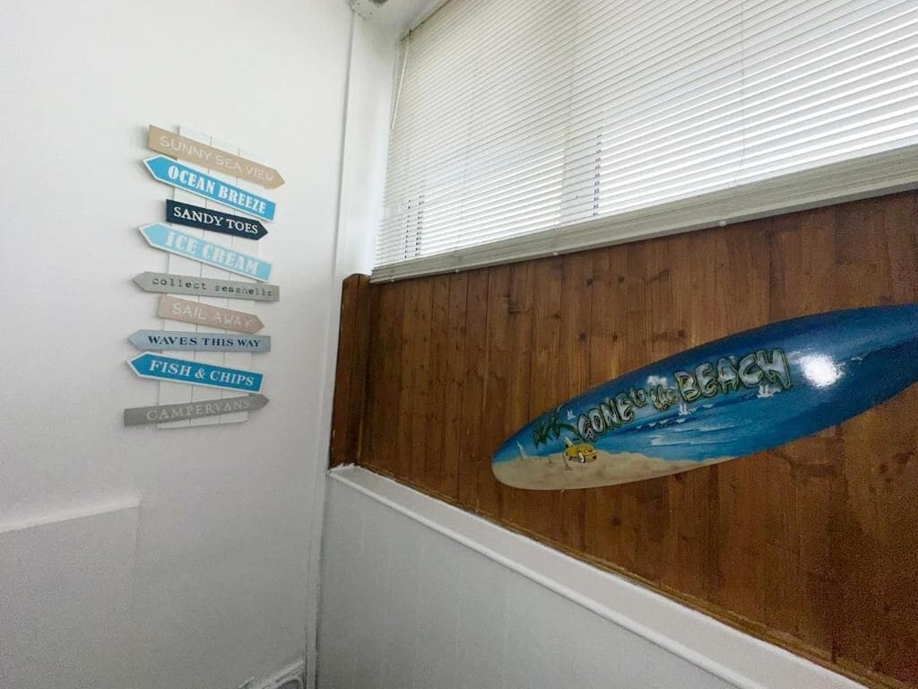 A wall with directional signs and a surfboard.