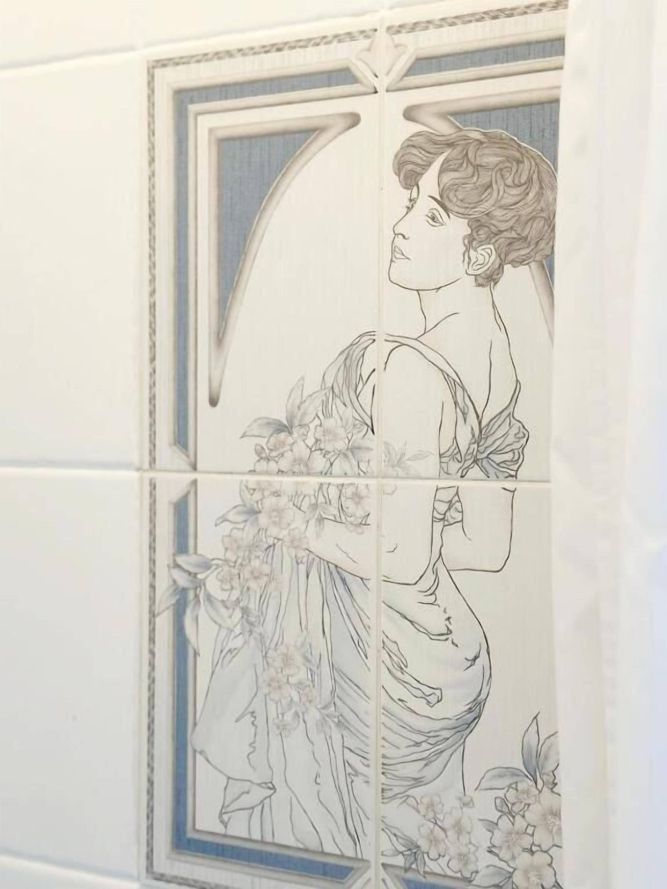 Pared de azulejos con un detallado dibujo lineal de una mujer con vestido rodeada de flores.