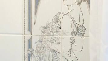 Pared de azulejos con un detallado dibujo lineal de una mujer con vestido rodeada de flores.
