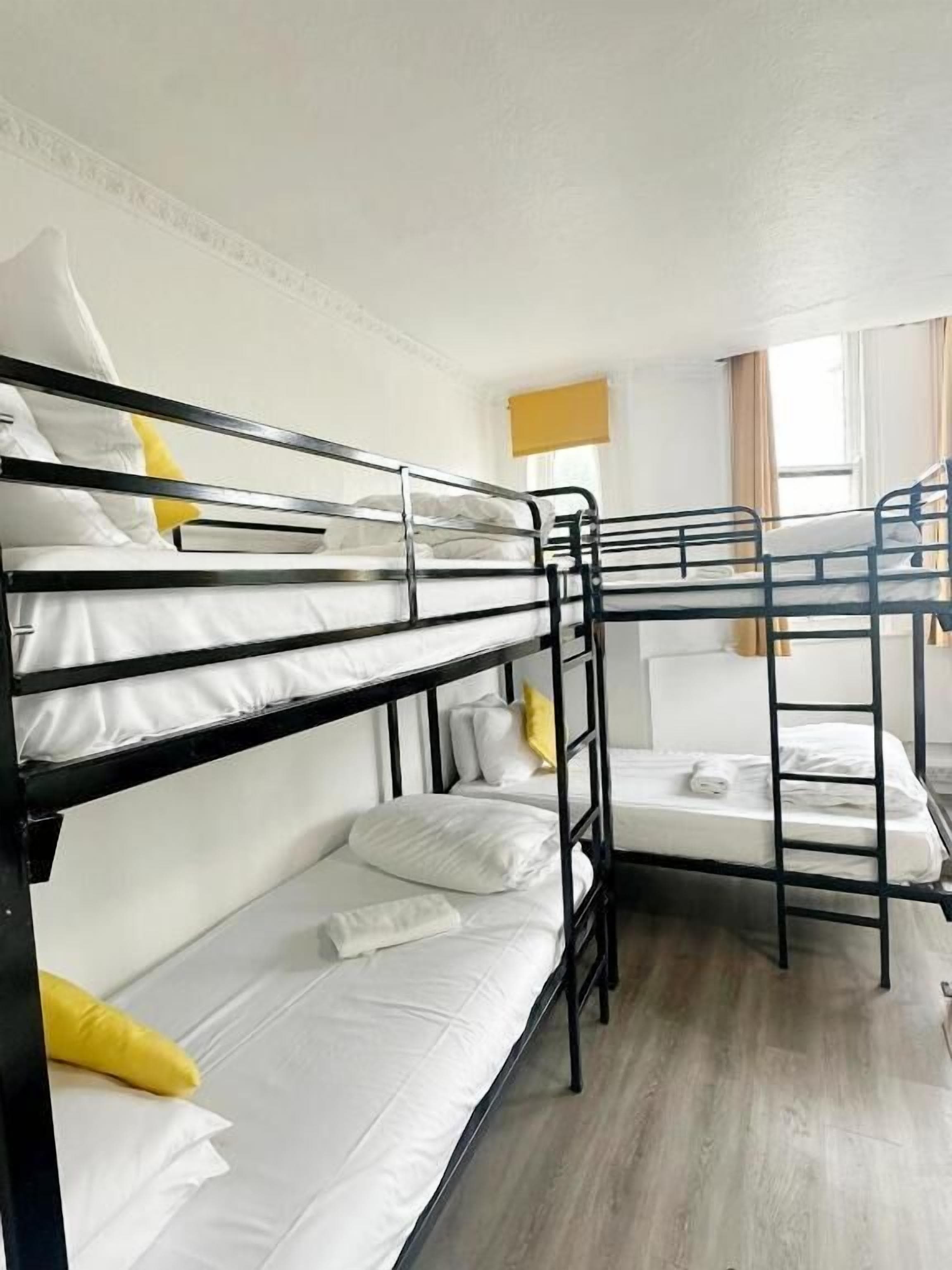 A bunk bed room with white bedding and yellow pillows.