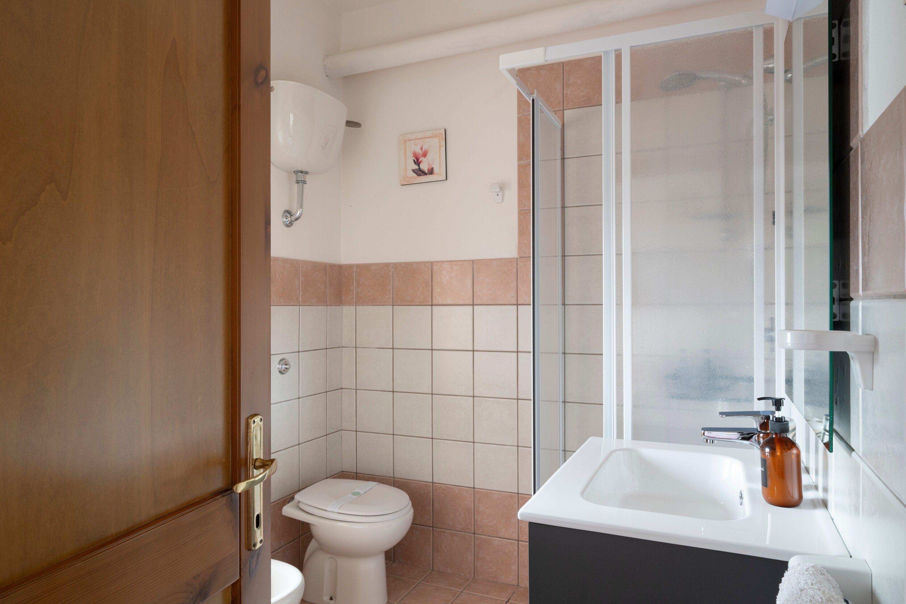 A bathroom with a toilet, sink, and shower.