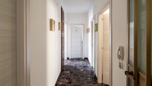 Käytävä, jossa on marmorilattia, valkoiset seinät ja ovet molemmin puolin.