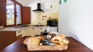A kitchen with wooden cabinets, a microwave, a sink, and a countertop with food items and a wine glass.