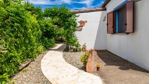 A stone pathway leading to a building with a white exterior and brown shutters.