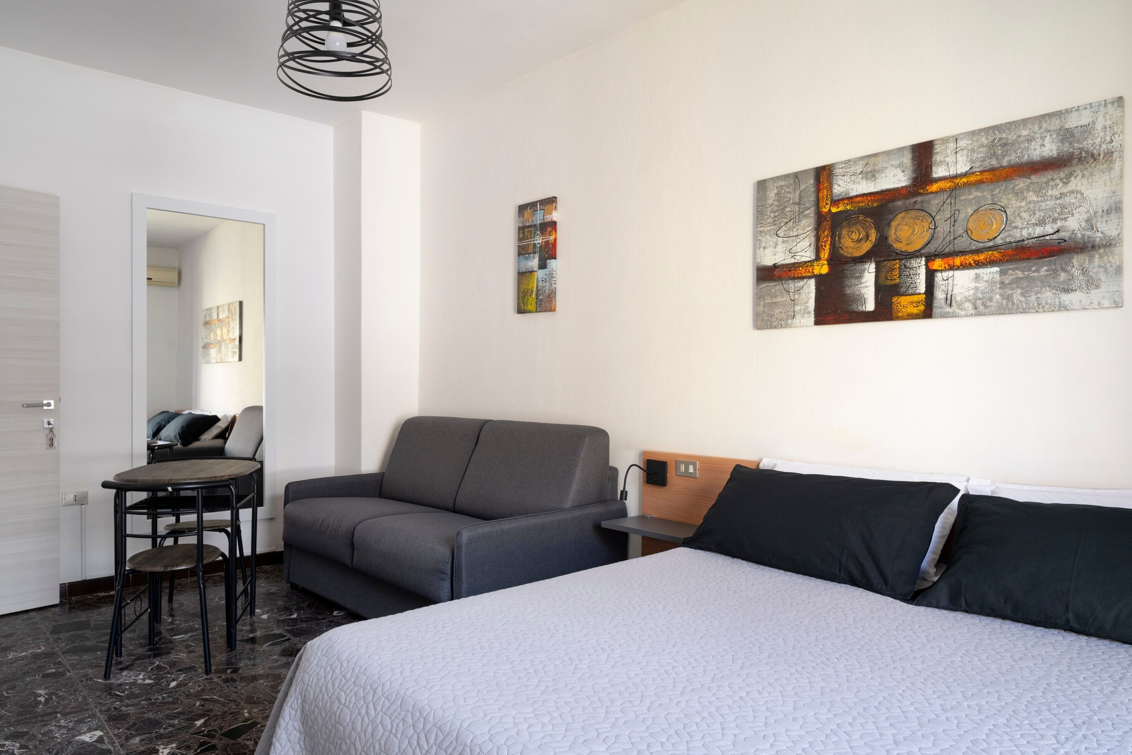 Et hotelværelse med seng, sofa, skrivebord og stol.