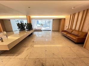 Un vestíbulo moderno con una mesa de recepción, un sofá y un amplio ventanal.