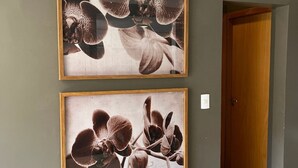 Dos cuadros enmarcados con orquídeas en una pared de un pasillo.