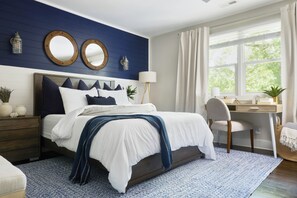 Ein Schlafzimmer mit Bett, Nachttischen, Schreibtisch und einem Fenster mit Vorhängen.