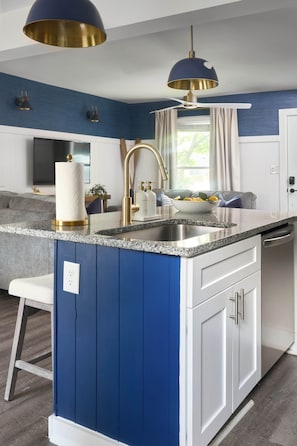 Eine moderne Küche mit blauer Akzentwand, Edelstahlgeräten und Pendelleuchten.