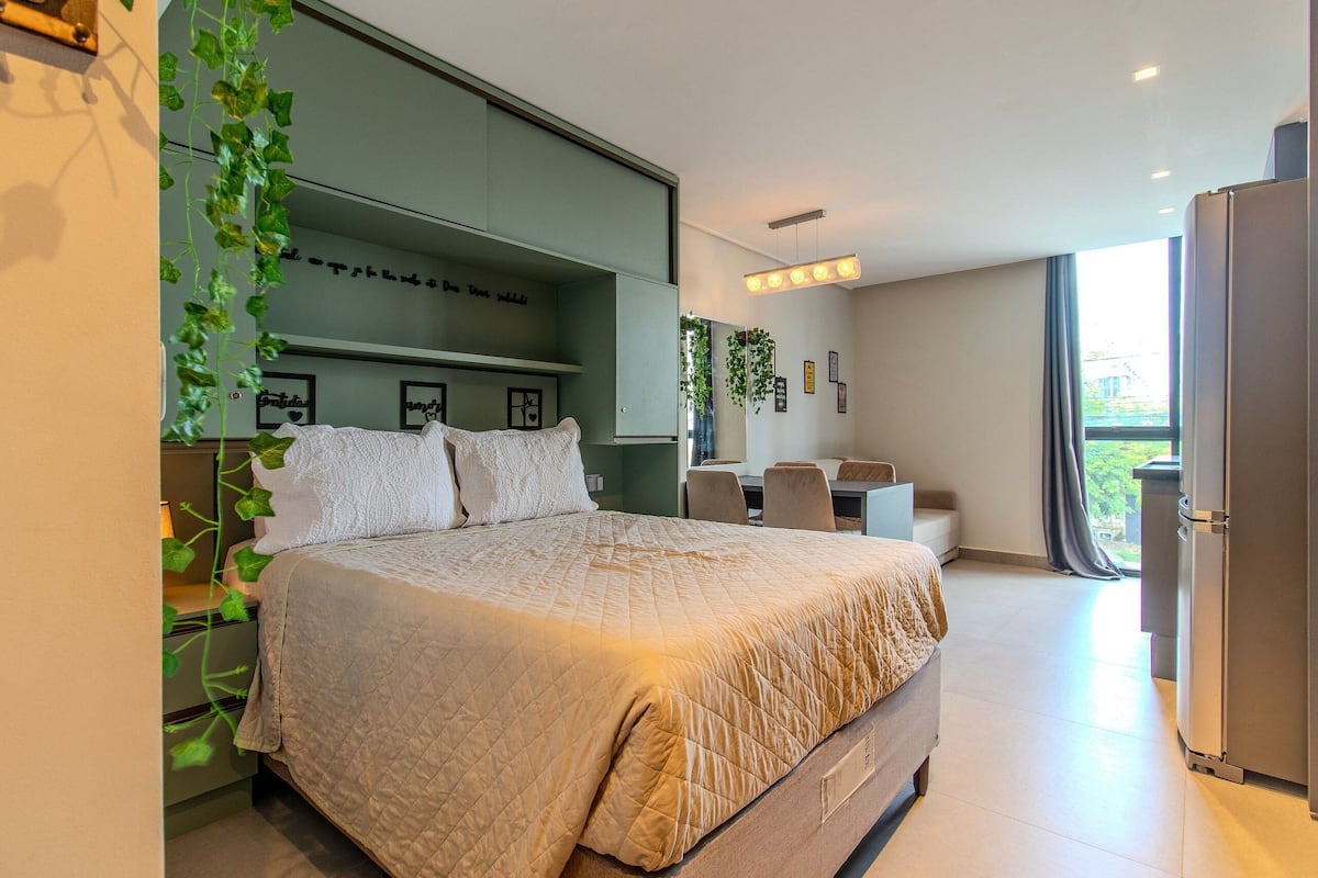 Quarto moderno com uma cama grande, uma escrivaninha e vista para o exterior.
