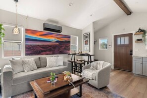 Ein modernes Wohnzimmer mit einem grauen Sofa, einem Holztisch und einem Gemälde vom Sonnenuntergang.