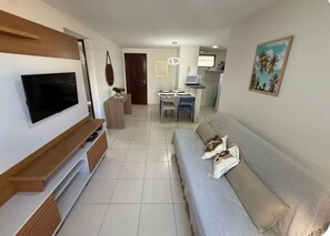 Ein Wohnzimmer mit Fernseher, Sofa und Essbereich.