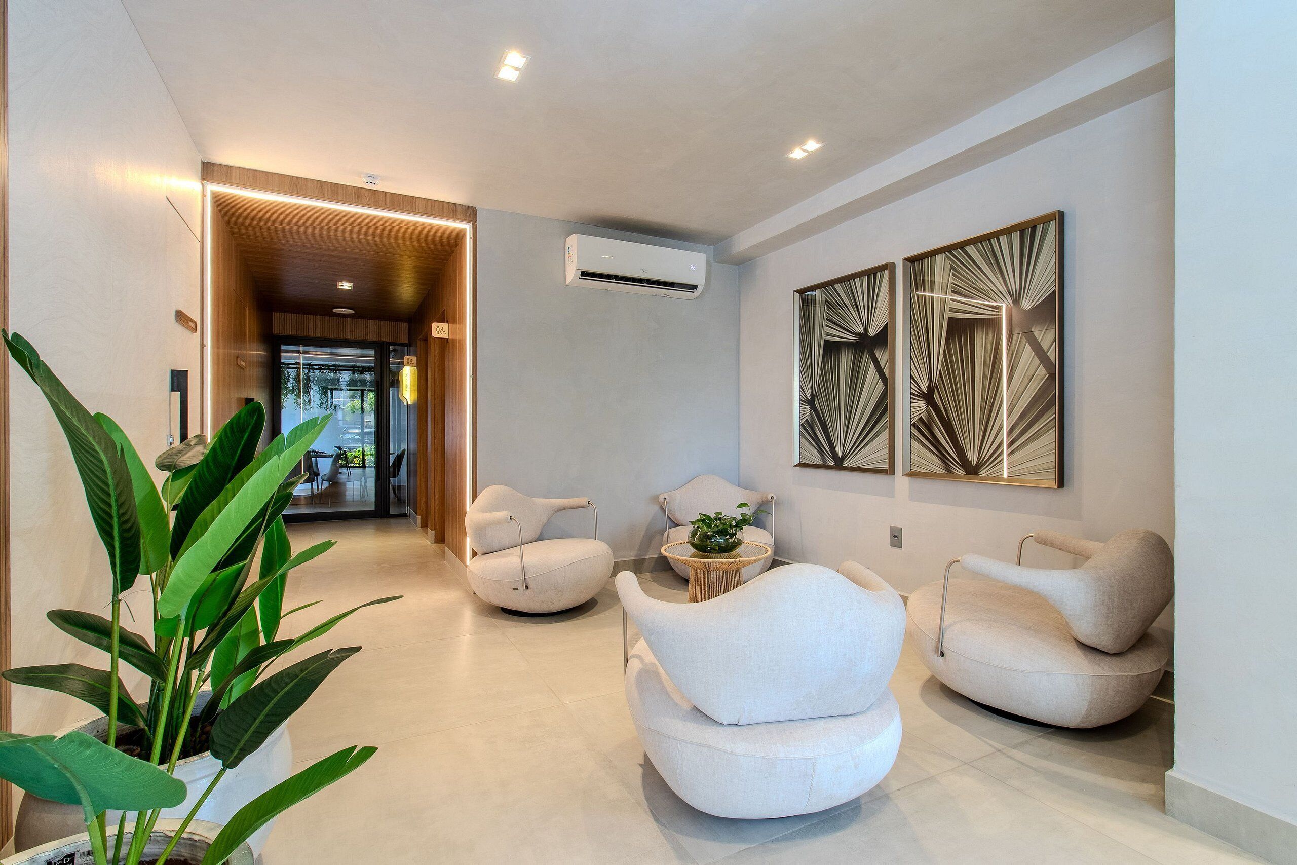 Un interior moderno con una zona de estar, una planta en maceta y un pasillo que conduce a otra habitación.