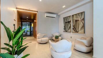 Un interior moderno con una zona de estar, una planta en maceta y un pasillo que conduce a otra habitación.