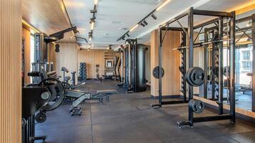 A gym with weightlifting equipment, mirrors, and a wooden wall.