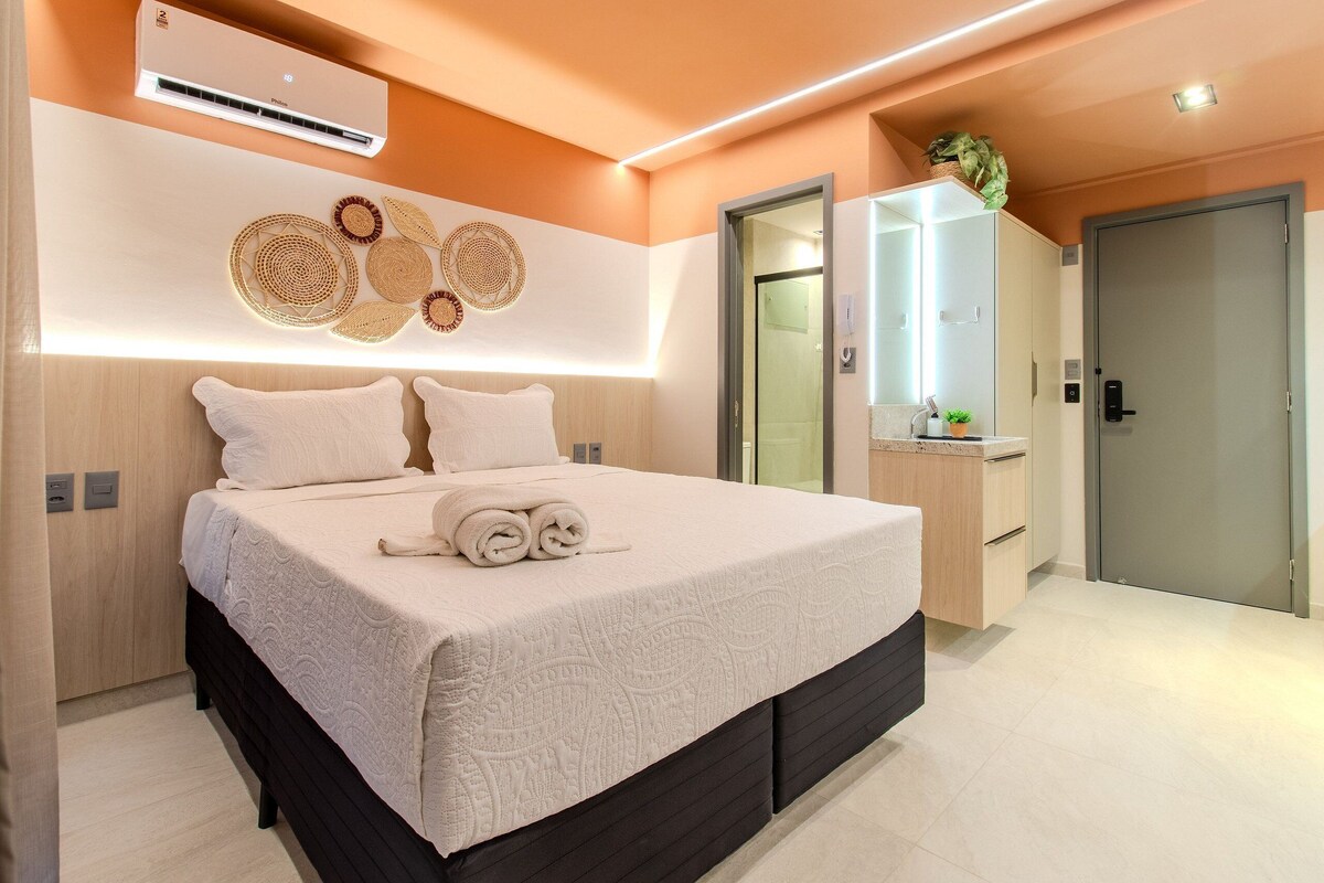 Un dormitorio moderno con una cama grande, mesitas de noche, un armario empotrado y un baño con espejo y lavabo.