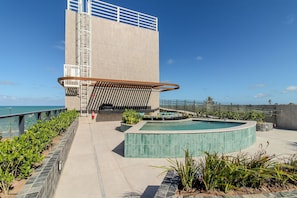 Ein modernes Gebäude mit Pool, Metalltreppe und Meerblick.